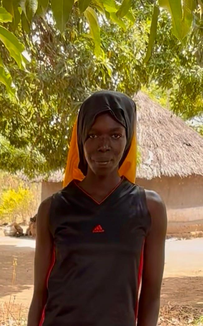 Portrait of Akello, a young shea harvester outside her home in Kitgum District